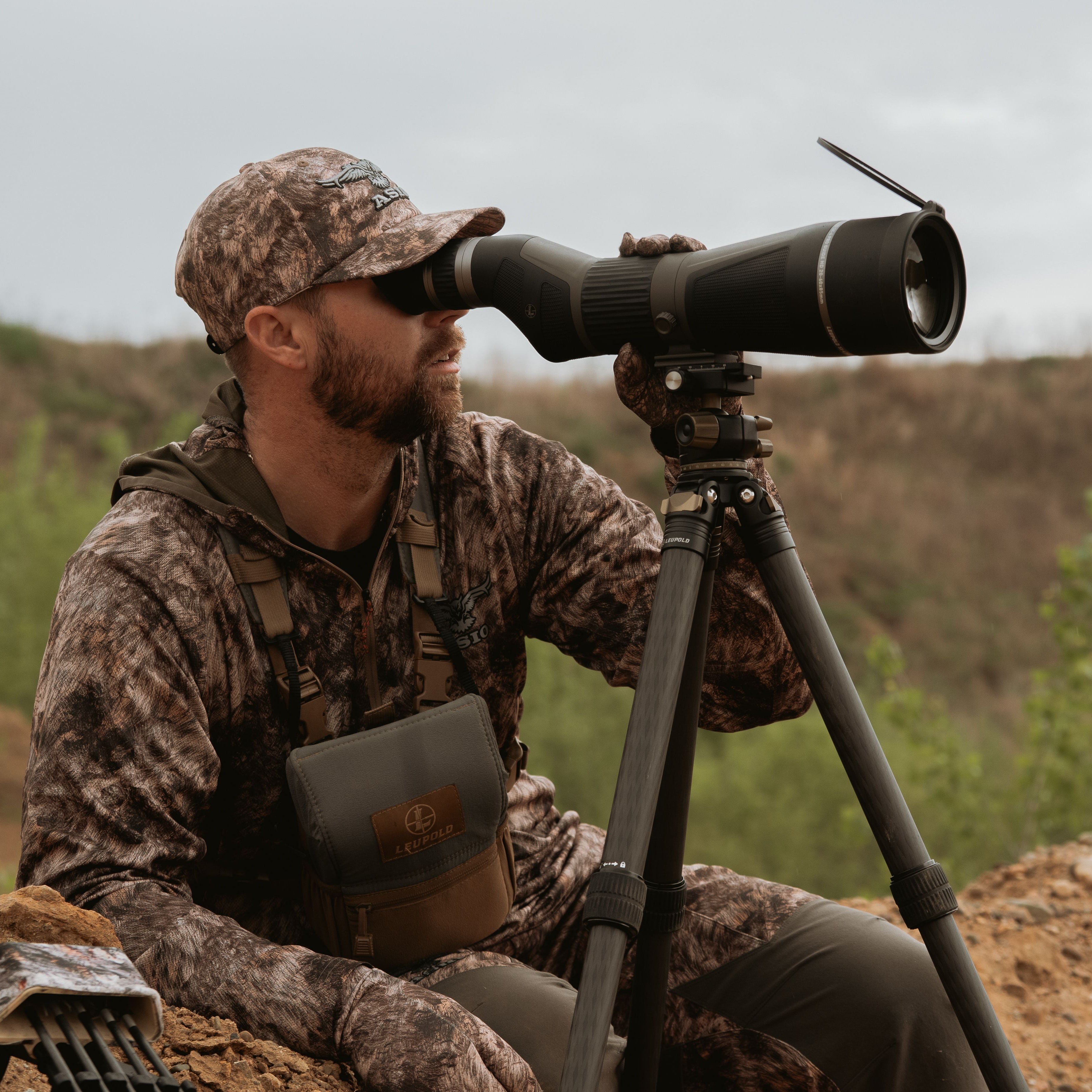 hunter wearing asio rapx camo using spotting scope to locate whitetails on western plains