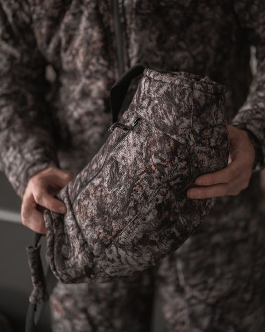 Close-up of ASIO Gear handmuff in Raptor camo highlighting pocket zipper and ergonomic contour.
