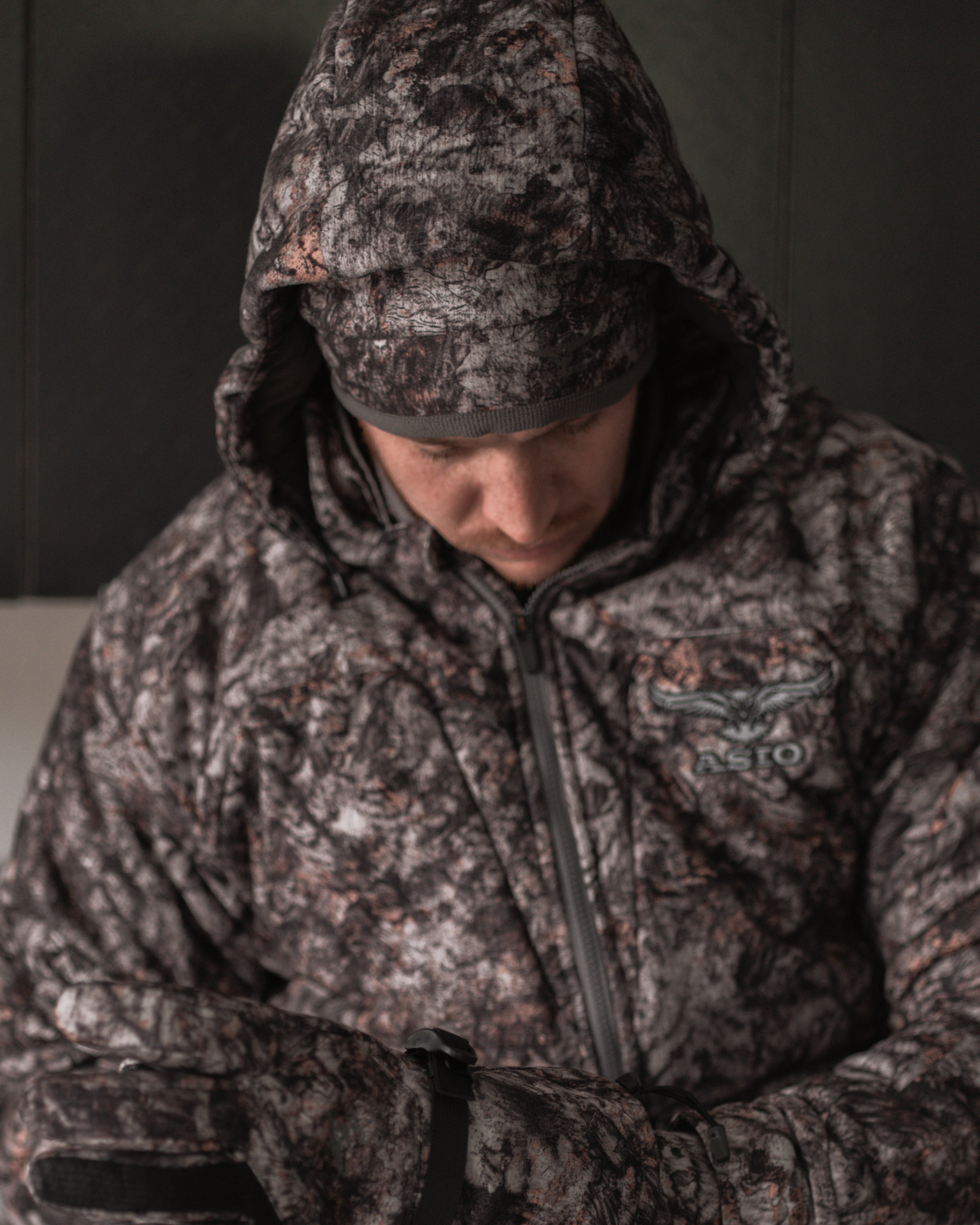 Hunter in ASIO Gear RAPTOR camo heavyweight hooded jacket and gloves preparing for late-season whitetail hunt