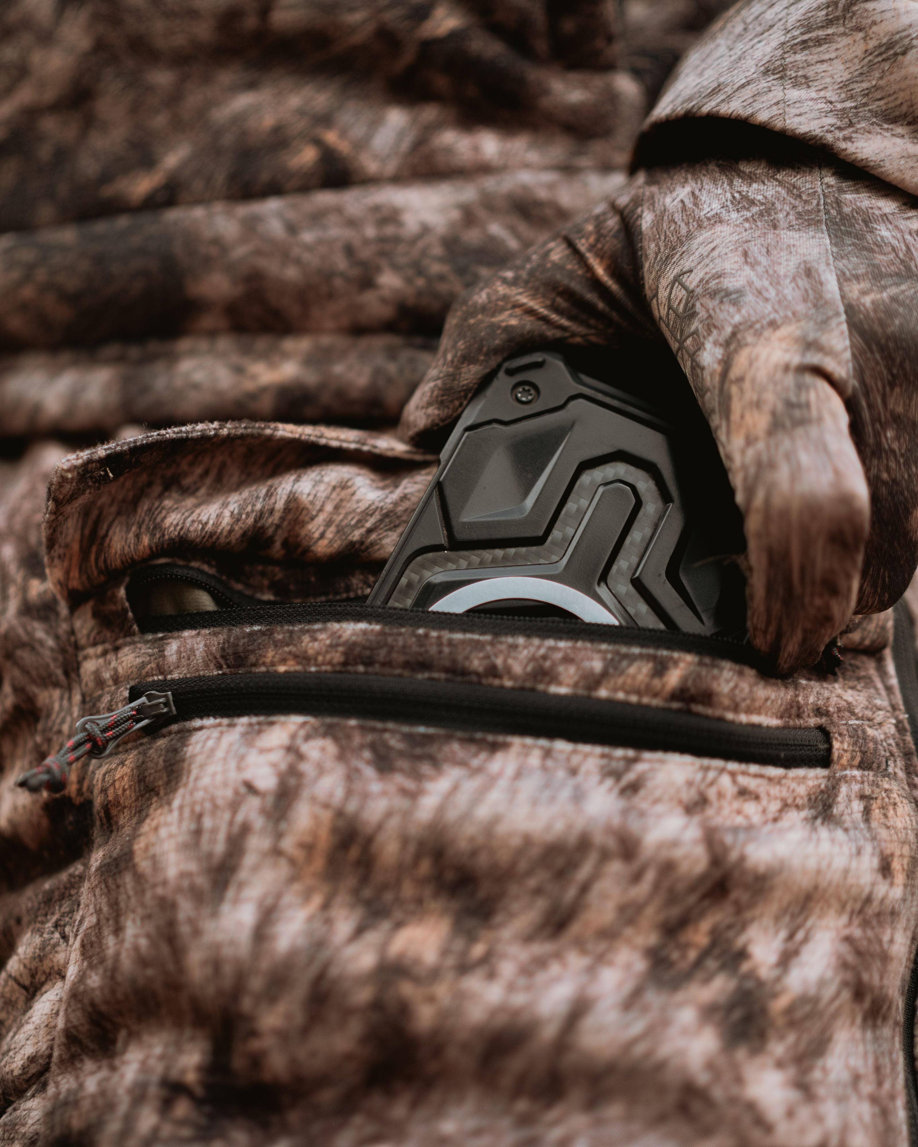 Closeup of gear stowed in thigh zipper pocket of ASIO Midweight Sherpa Pant in RAPX camo during bowhunt.