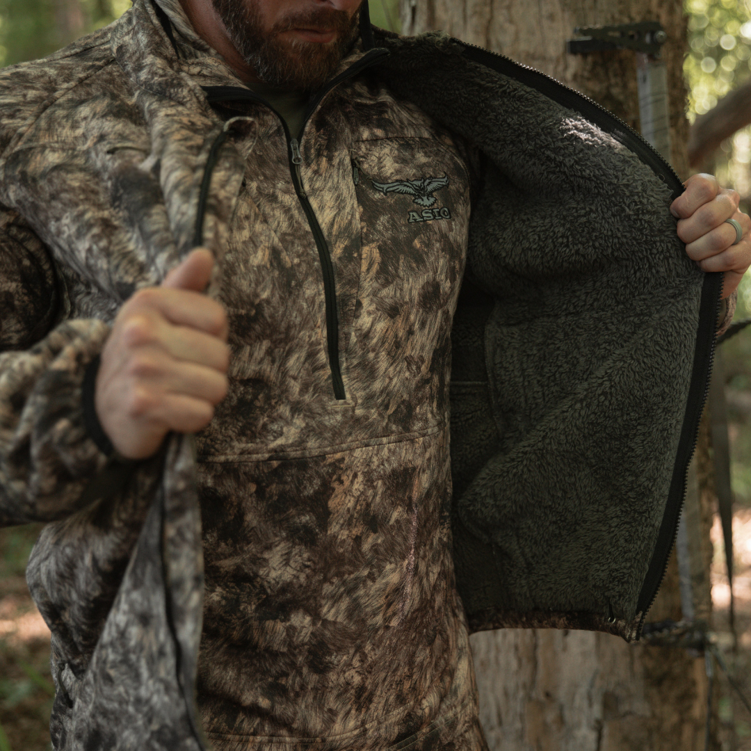 ASIO Gear wearing rapx windproof sherpa fleece hunting jacket getting dressed at base of whitetail deer treestand