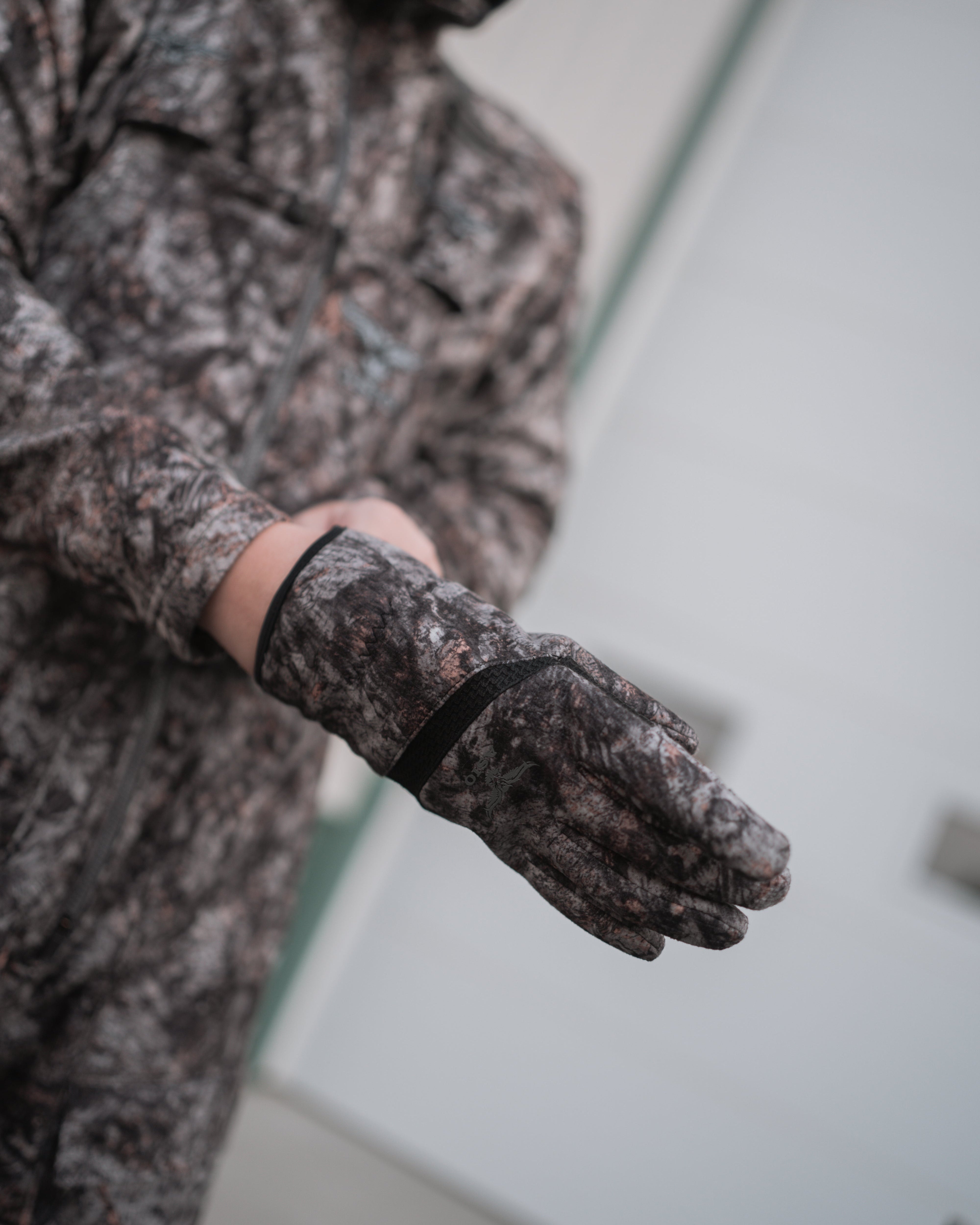 hunter slipping on sherpa windproof bowhunter glove in raptor camo