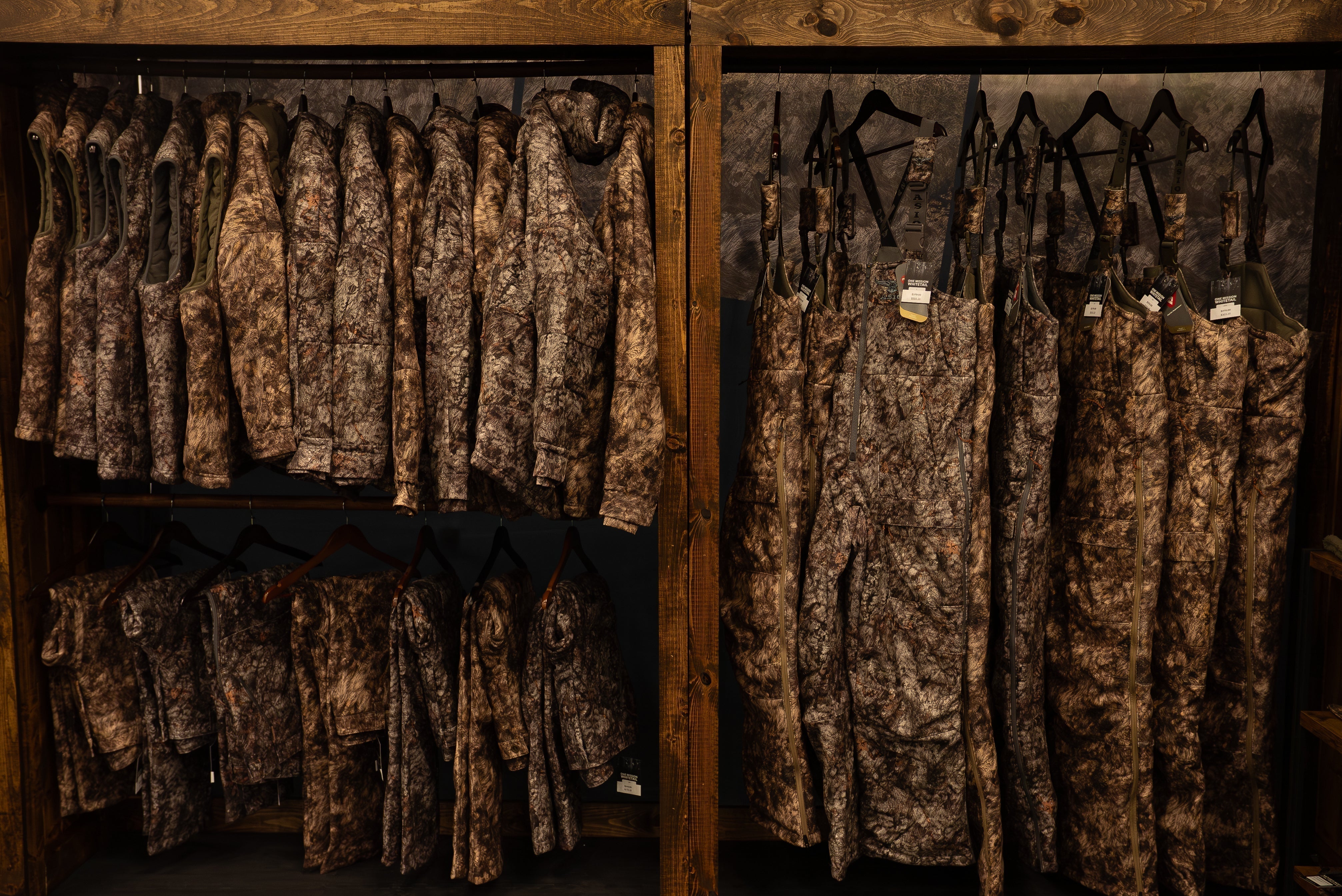 ASIO Gear whitetail bowhunting jackets and bibs displayed at a trade show, showing camo patterns and layering systems up close