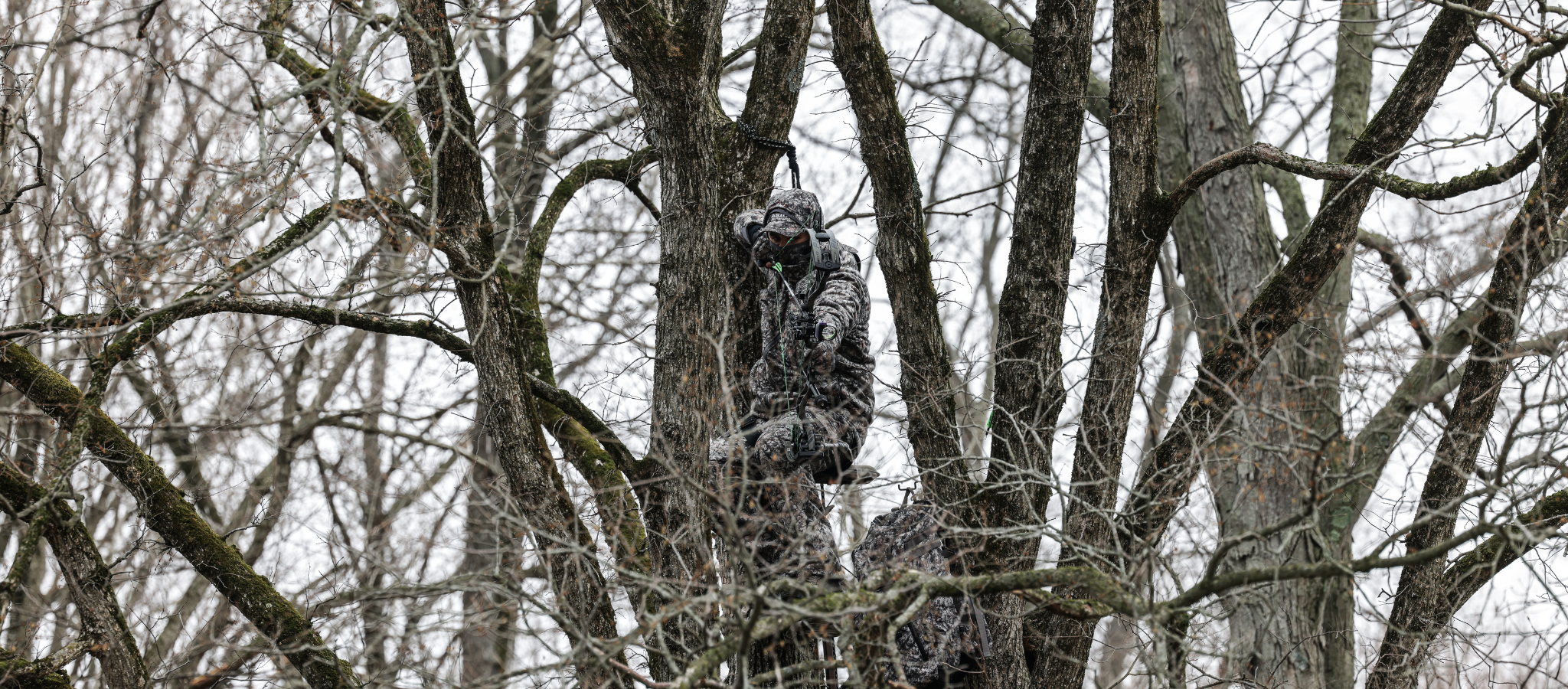 hunter wearing asio raptor camo at full draw on a whitetail during late season bow hunt