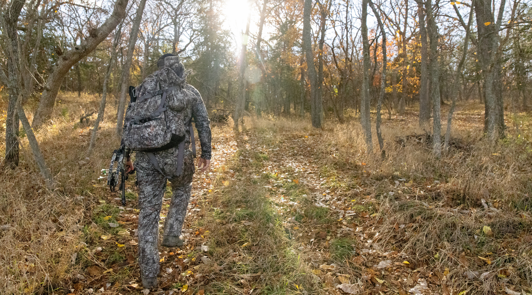 hunter wearing asio gear bowhunting gear walking into woods to hunt during whitetail rut.