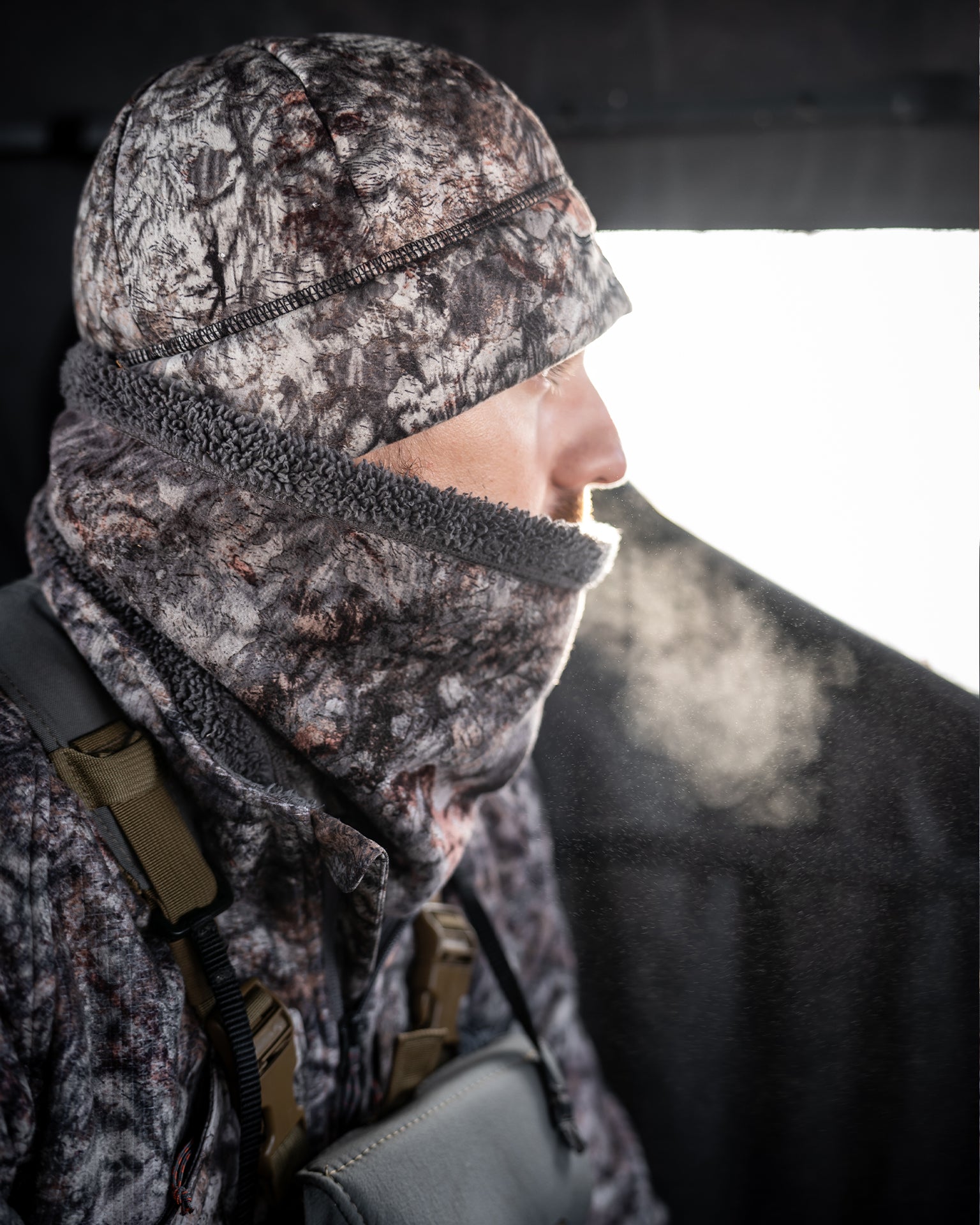 Bowhunter wearing the ASIO Gear Midweight Sherpa Neck Gaiter in RAPTOR camo during a cold weather treestand hunt with sherpa fleece lining for warmth and concealment.